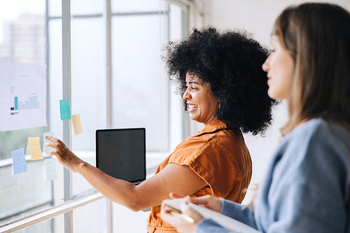 Happy young businesswomen brainstorming using sticky notes