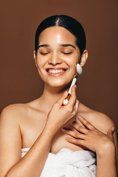 Creating radiance with a jade roller. Smiling woman massages her face with a beauty stone in a studio