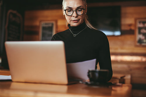 Senior businesswoman reviewing few documents at cafe