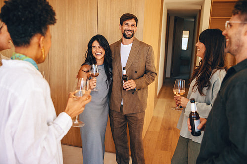 Happy couple enjoying drinks with close friends at a cozy home environment