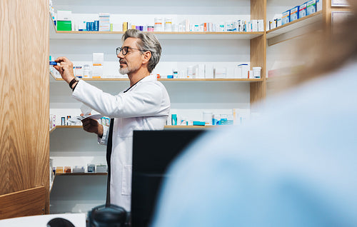 Male pharmacist assisting a patient with a prescription in a chemist
