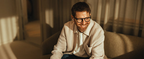 Business man smiles while sitting on a sofa in a relaxed office 