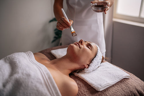 Woman getting facial mask at spa salon