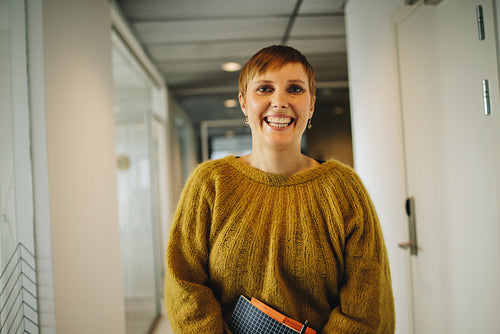 Happy woman standing in office corridor