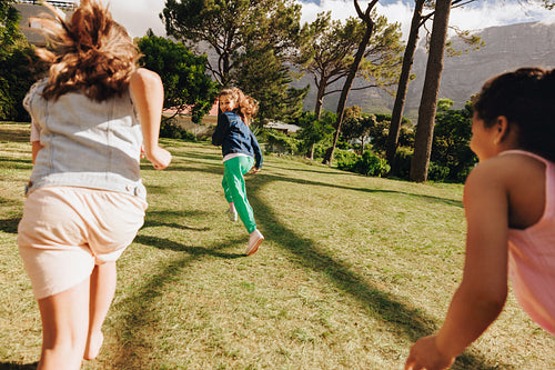 Children playing in a sunny park surrounded by trees and nature