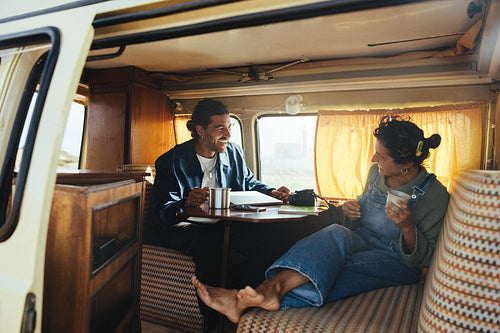 Couple enjoying coffee and conversation in a cozy camper van during a road trip