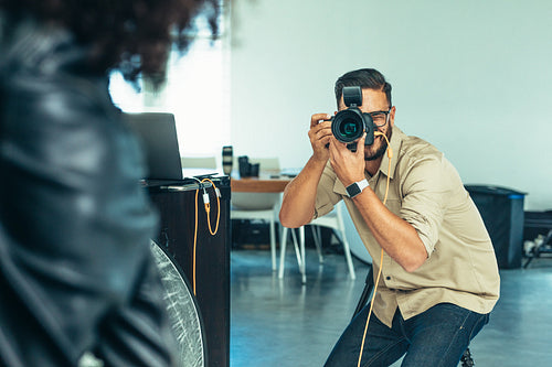 Photographer bending down to take a photo of a model