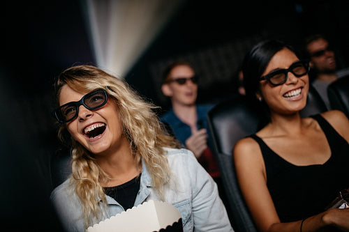 Female friends watching 3d movie and laughing 
