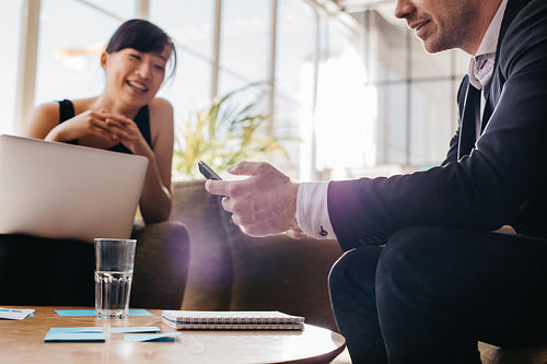 Young business man using mobile phone in meeting