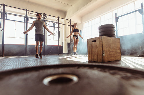 Fit couple jumping ropes in cross training gym