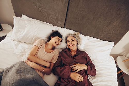 Top view of happy daughter and mother lying on bed at home