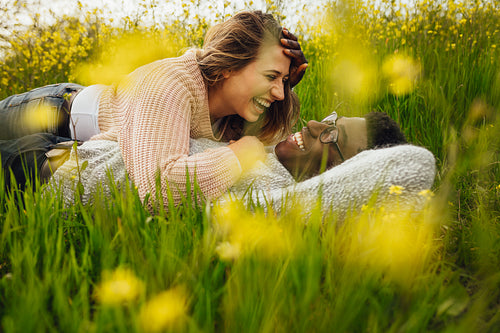 Interracial couple lying on grass and laughing