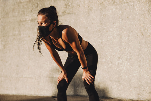 Sporty woman with mask taking rest after workout
