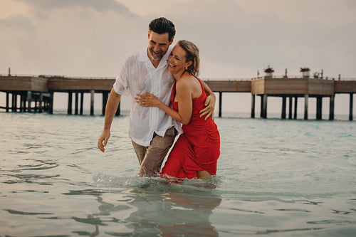 Romantic couple embracing in the ocean on luxury holiday getaway