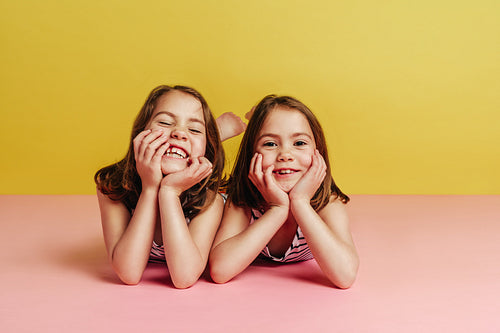 Twin girls lying on pink floor