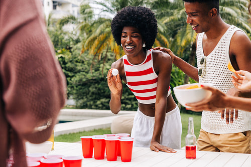Friends play beer pong at outdoor party