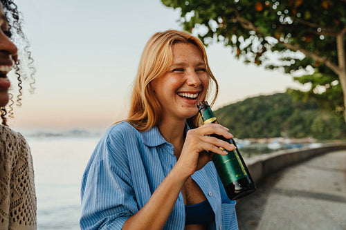 Joyful woman enjoying a beer by Mureta Da Urca at sunset