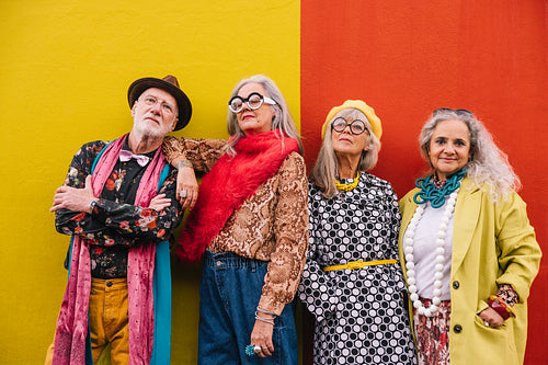 Vibrant elderly people standing together against a wall