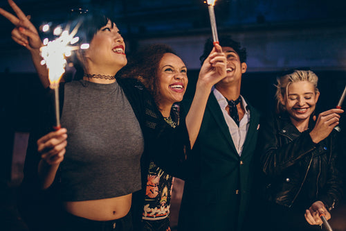 Group of friends having night party with sparklers