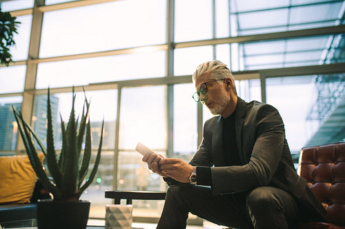 Senior executive texting on cell phone in office lobby