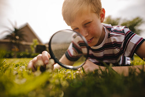 Boy exploring garden with his magnifying glass