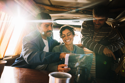 Friends on a road trip reading a map together inside a van