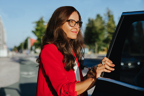 Confident woman opening car door on a clear sunny day