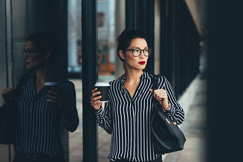 Businesswoman outside office building with a coffee