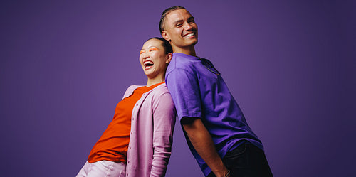Smiling friends stand back to back in a vibrant studio setting