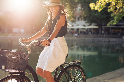 Happy young female cycling by a pond