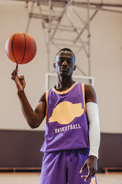 Athlete spinning basketball while wearing stylish uniform on indoor court