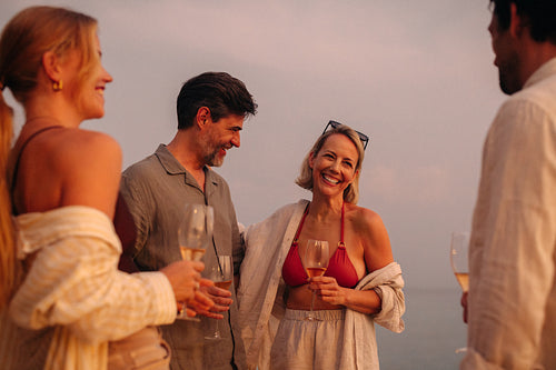 Friends enjoying sunset moments together with drinks by the ocean