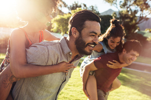 Couples playing piggyback ride race in backyard
