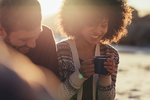 Smiling friends sitting at seashore