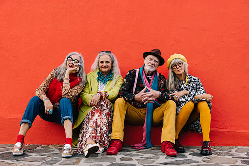 Group of senior citizens sitting against a red wall