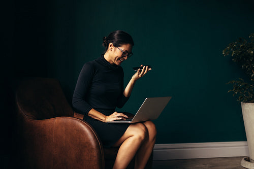 Young woman answering call and working on laptop