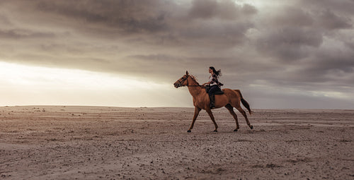 Woman horse ride on beach at sunset