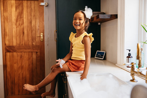Happy little girl playing with soap bubbles in the kitchen
