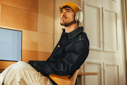 Pensive man works with headphones at a computer desk