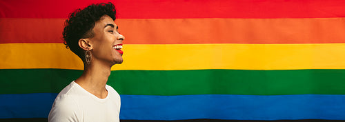 Transgender male smiling against pride flag