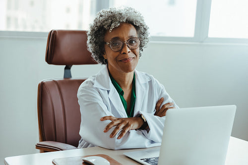Confident dentist working at desk with laptop in professional healthcare office