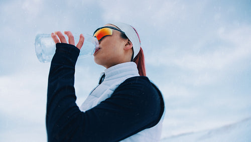 The woman takes a drinking break during winter running training in snow