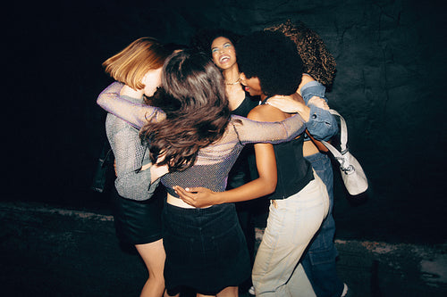 Friends embracing and dancing together during a joyous night out celebration.