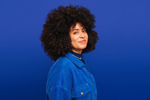 Portrait of a happy young woman standing against a blue background