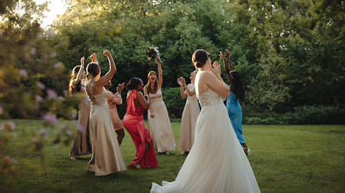 Bride and bridesmaids celebrating bouquet toss at a beautiful outdoor wedding