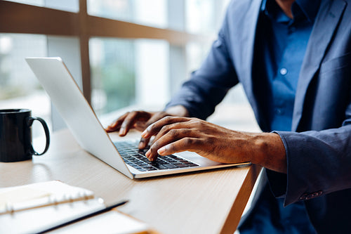 Professional working at a desk using a laptop with hands on the keyboard