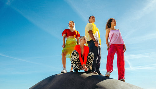 Outdoor friends pause together on a hilltop beneath blue sky