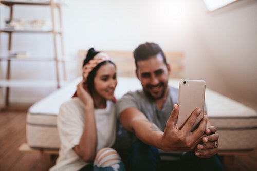 Young couple sitting at home taking selfie