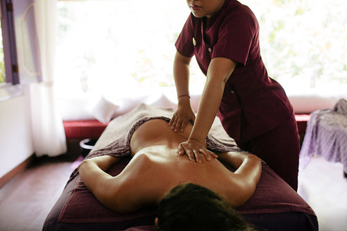 Massage therapist hands massaging back of a woman