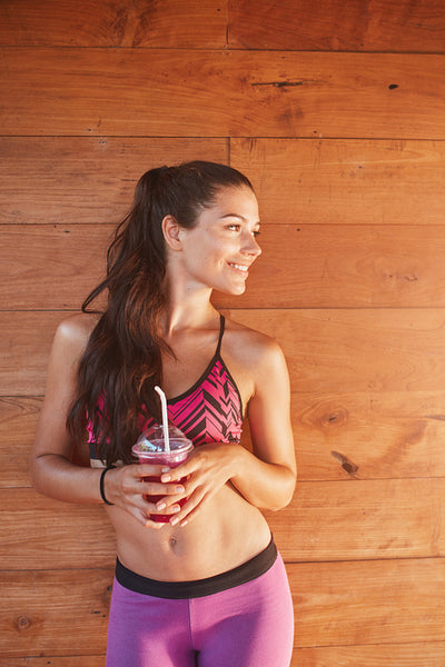 Sportswoman holding glass of juice and looking away